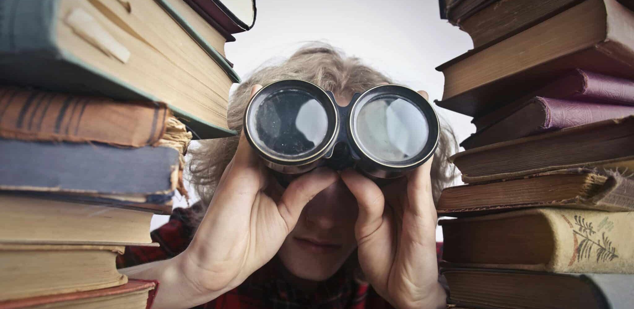 kvinna kikar ut i kikare mellan böcker